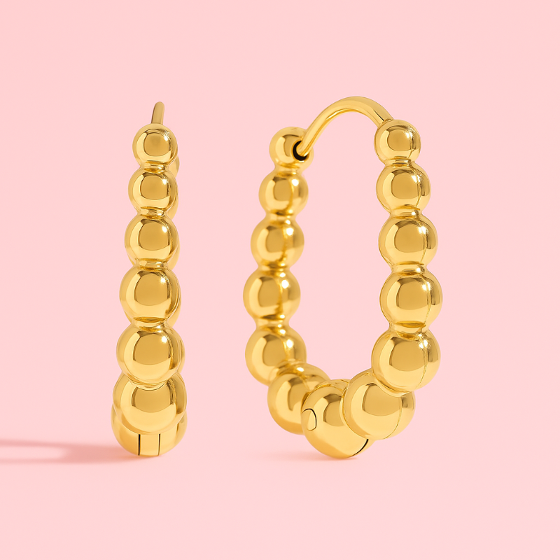 Gold hoop earrings on a pink background