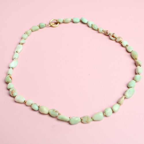 Mint green beaded necklace on a pink background