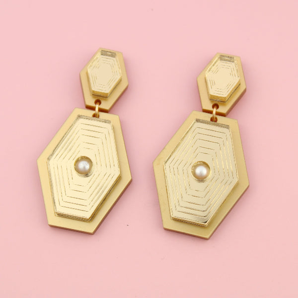Gold geometric earrings with pearl centers on a pink background