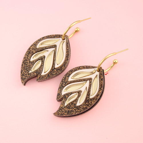 Leaf-shaped earrings on a pink background
