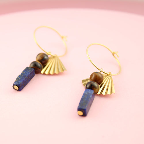 Pair of gold earrings with blue and brown beads on a pink background