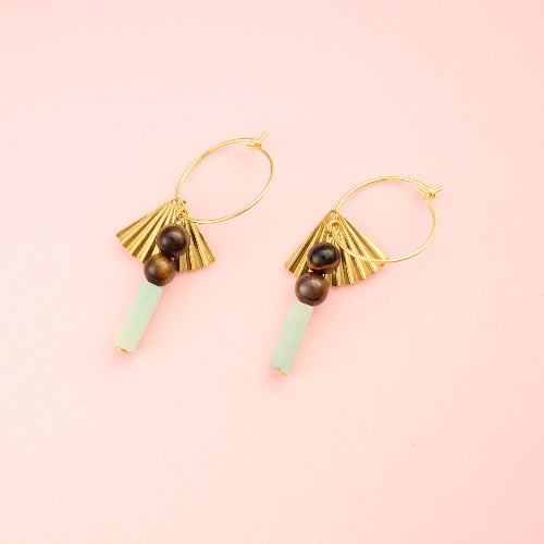 Gold earrings with green beads on a pink background