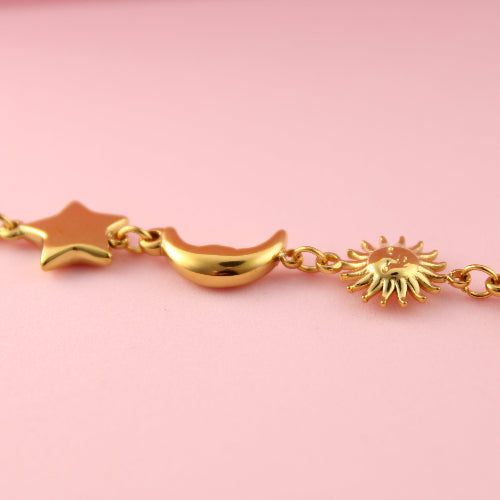 Gold bracelet with star, moon, and sun designs on a pink background