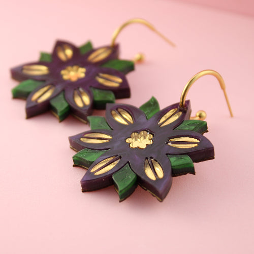Floral earrings with green and gold design on a pink background