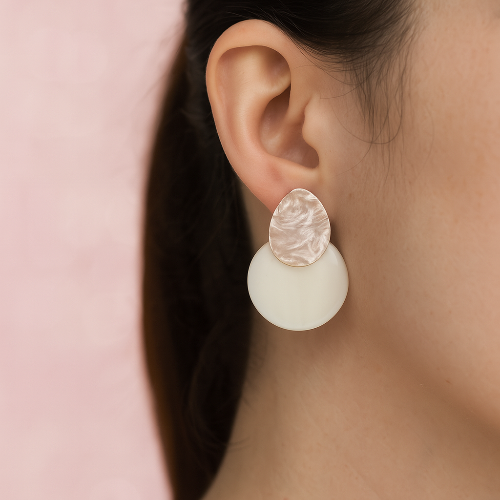 Close-up of a person wearing a white earring  on a pink background