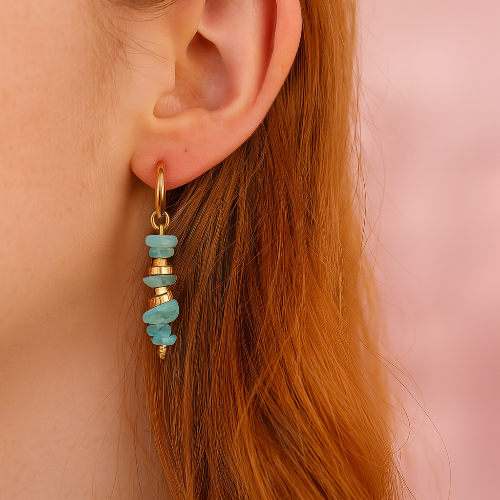 Close-up of an ear wearing a turquoise beaded earring against a pink background