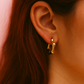 Gold earring worn by a person with dark hair.
