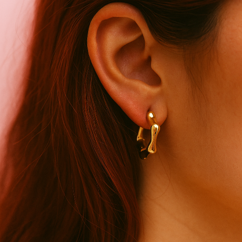 Gold earring worn by a person with dark hair.