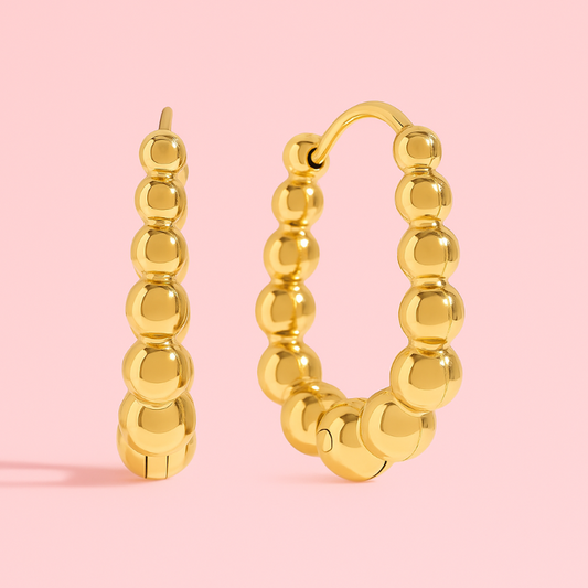 Gold hoop earrings on a pink background