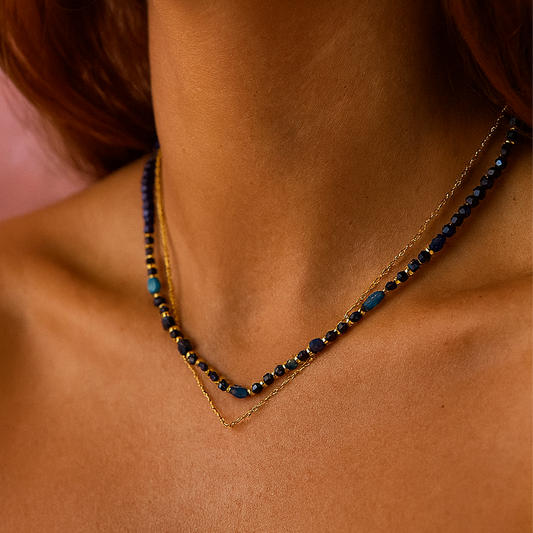 Necklace with blue beads on a person's neck against a pink background