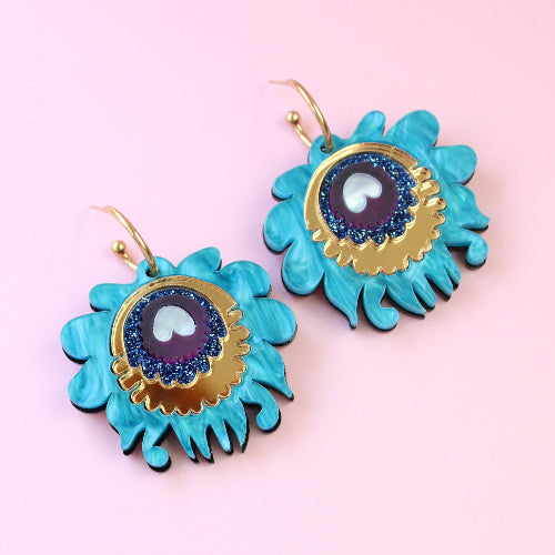 Turquoise earrings with gold accents on a pink background