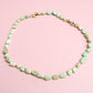 Mint green beaded necklace on a pink background