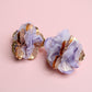Pair of floral earrings with gold accents on a pink background