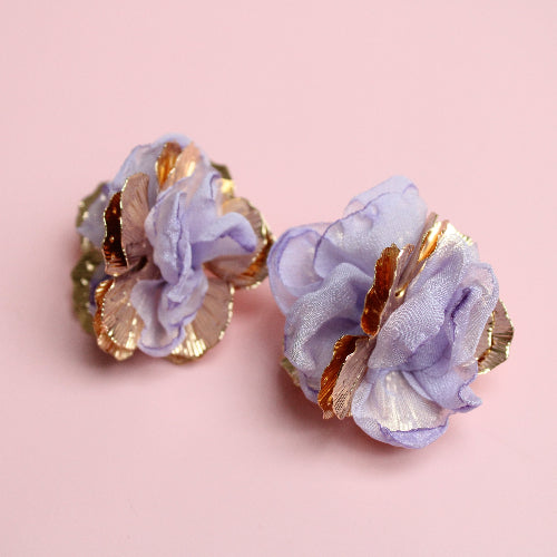 Pair of floral earrings with gold accents on a pink background