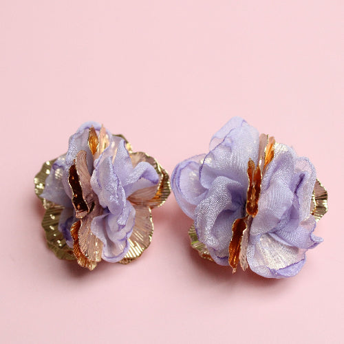 Pair of purple floral earrings with gold accents on a pink background