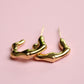 Gold hoop earrings on a pink background