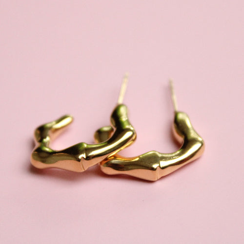Gold hoop earrings on a pink background