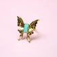 Gold butterfly ring  with a turquoise center on a pink background