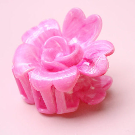 Pink flower-shaped hair clip on a pink background
