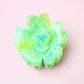 Green flower-shaped hair clip on a light pink background
