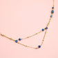 Gold necklace with blue beads on a pink background
