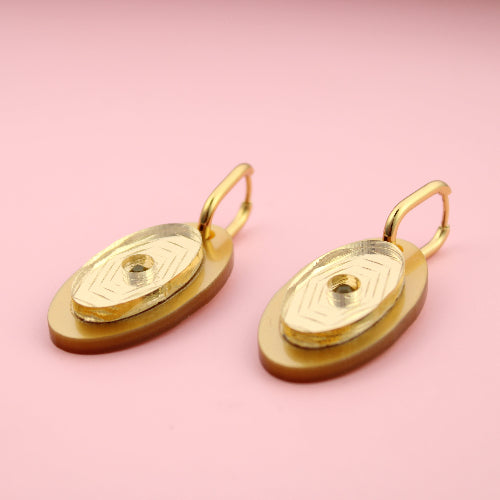 Gold earrings on a pink background