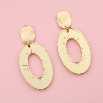 Gold earrings on a pink background