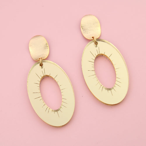 Gold earrings on a pink background