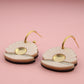Pair of earrings with gold accents on a pink background
