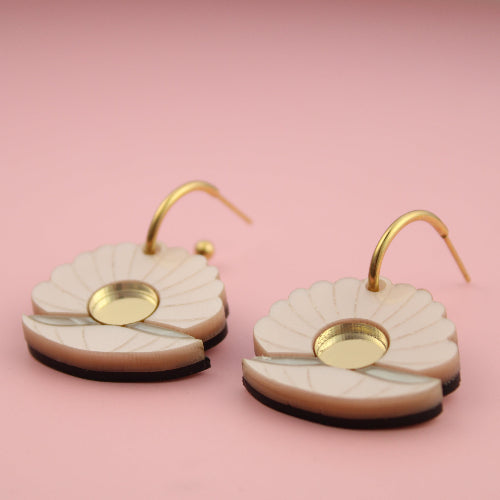 Pair of earrings with gold accents on a pink background