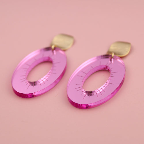 Pink earrings with gold hooks on a pink background