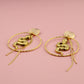 Gold earrings on a pink background
