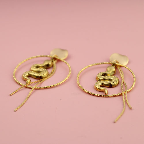 Gold earrings on a pink background