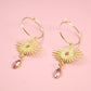 Gold earrings with pink gemstones on a pink background