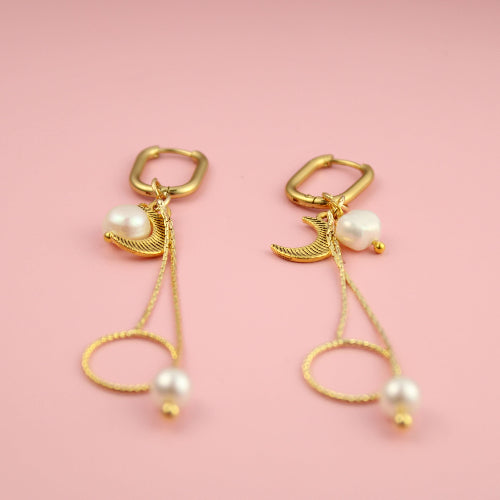 Gold earrings with pearls on a pink background