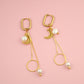 Gold earrings with pearls on a pink background