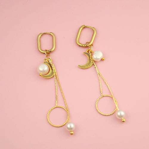 Gold earrings with pearls on a pink background