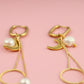 Gold earrings with pearl drops on a pink background