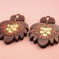 Pair of acrylic earrings with gold accents on a pink background
