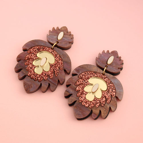 Pair of acrylic earrings with floral design on a pink background