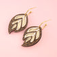 Leaf-shaped earrings on a pink background