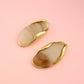 Pair of gold and beige earrings on a pink background