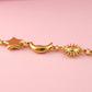 Gold bracelet with star, moon, and sun designs on a pink background