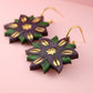 Floral earrings with green and gold design on a pink background
