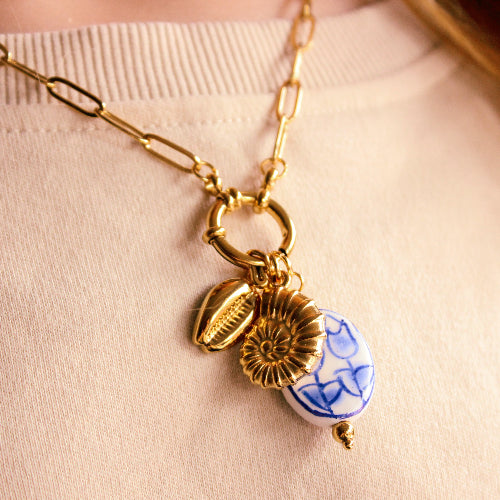 Gold necklace with charms on a beige background
