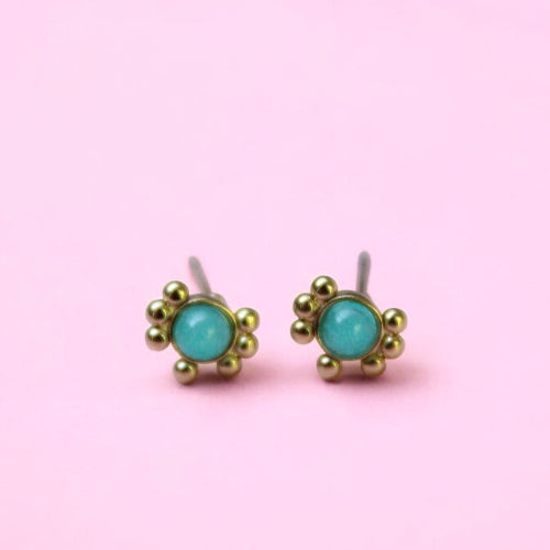 Gold earrings with turquoise stones on a pink background