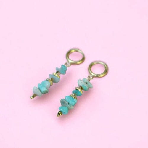 Pair of turquoise beaded earrings on a pink background